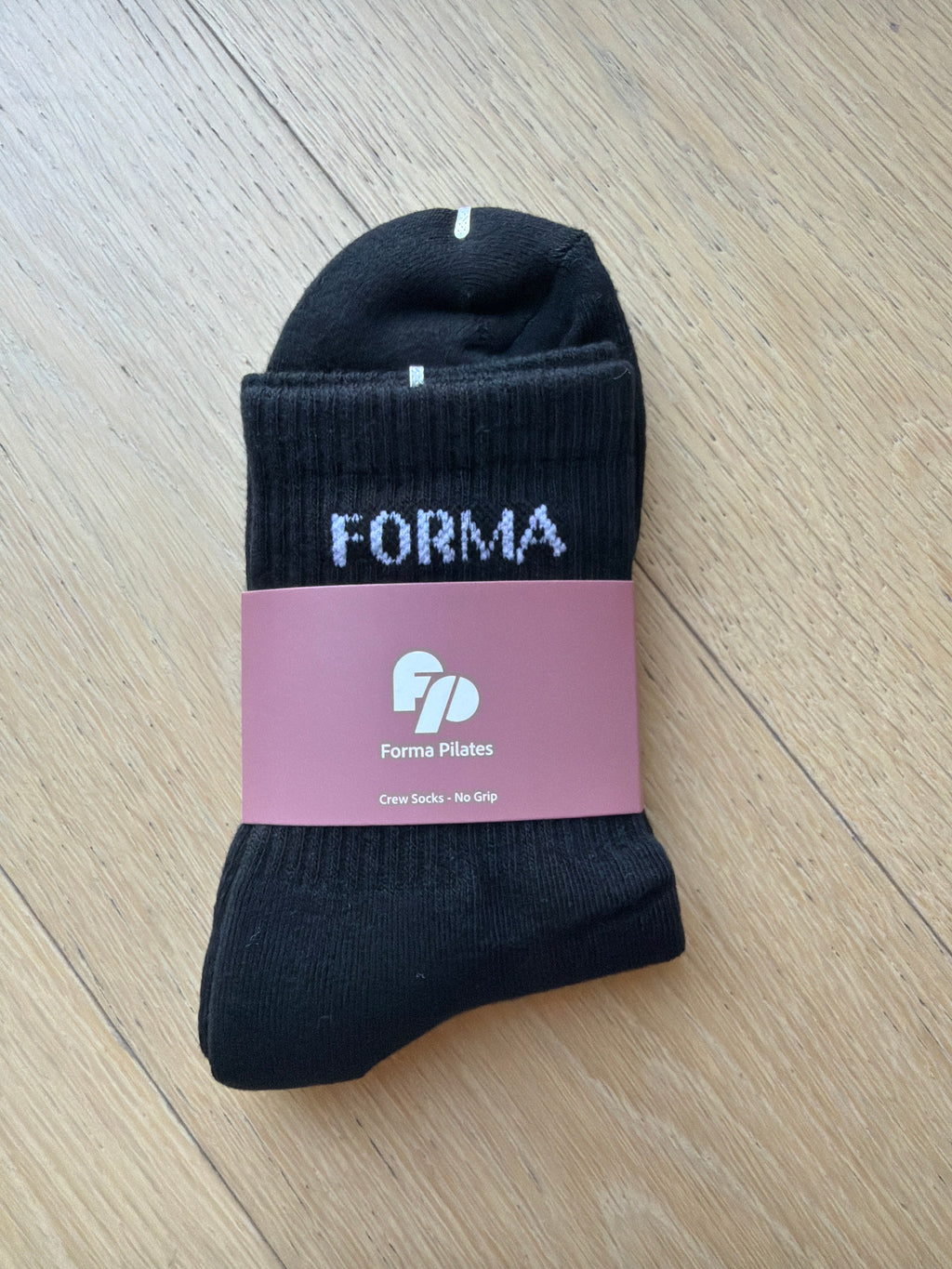 Black sock with a pink label on a wooden surface
