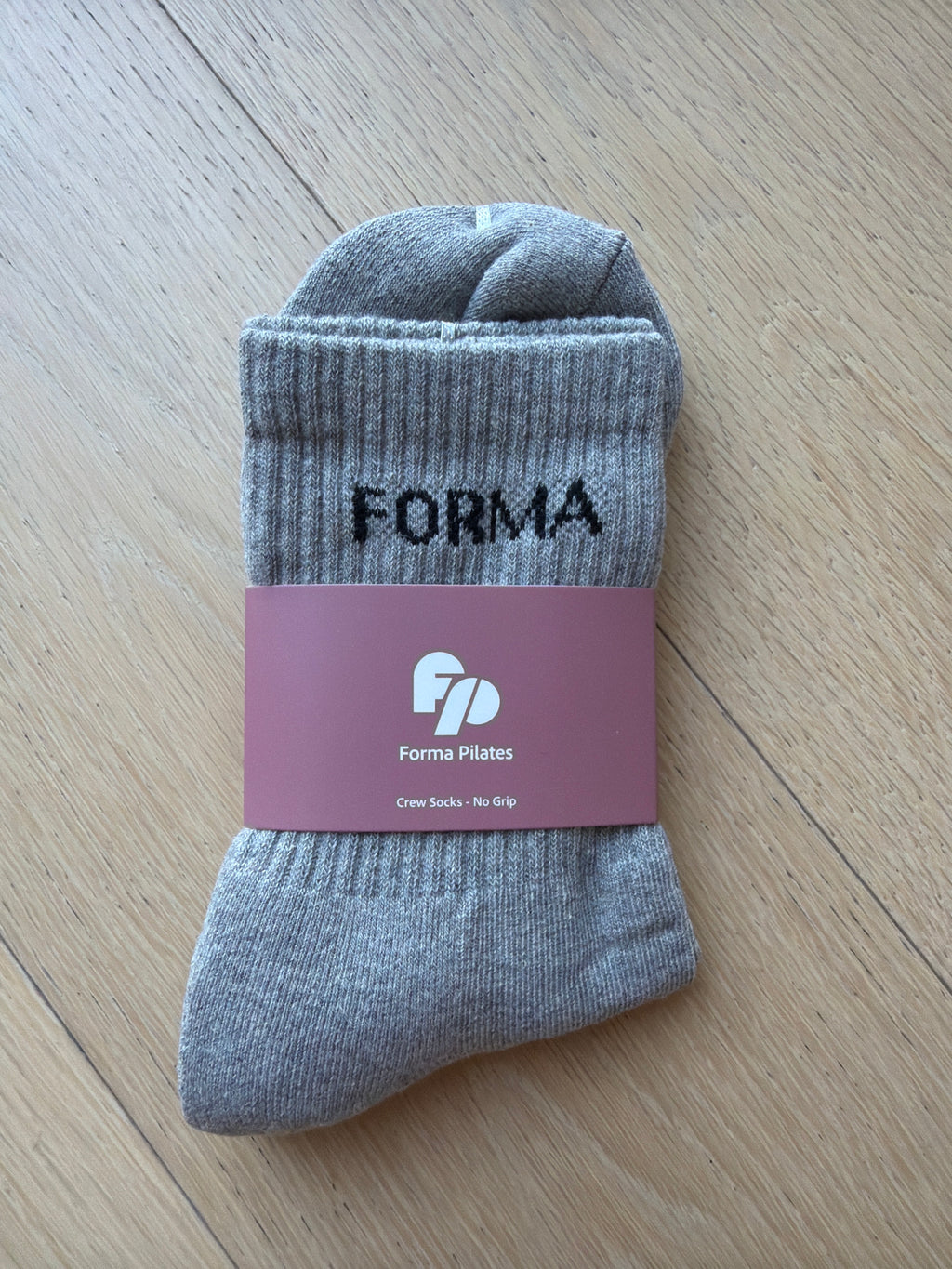 Gray sock with 'FORMA' branding on a wooden surface